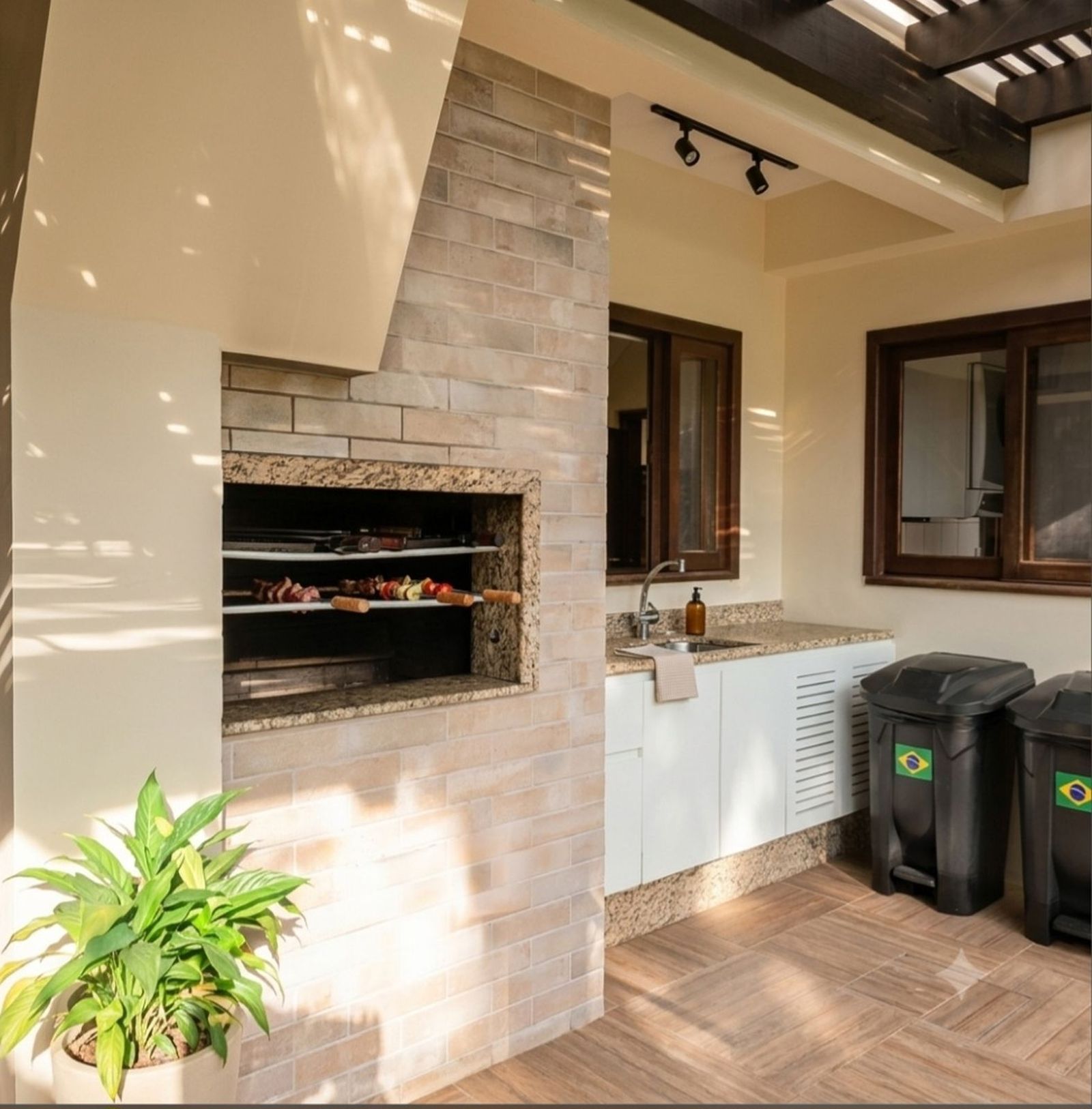 Varanda gourmet com churrasqueira integrada ao gramado, piscina e solarium em casa no Parque São Jorge, Itacorubi.