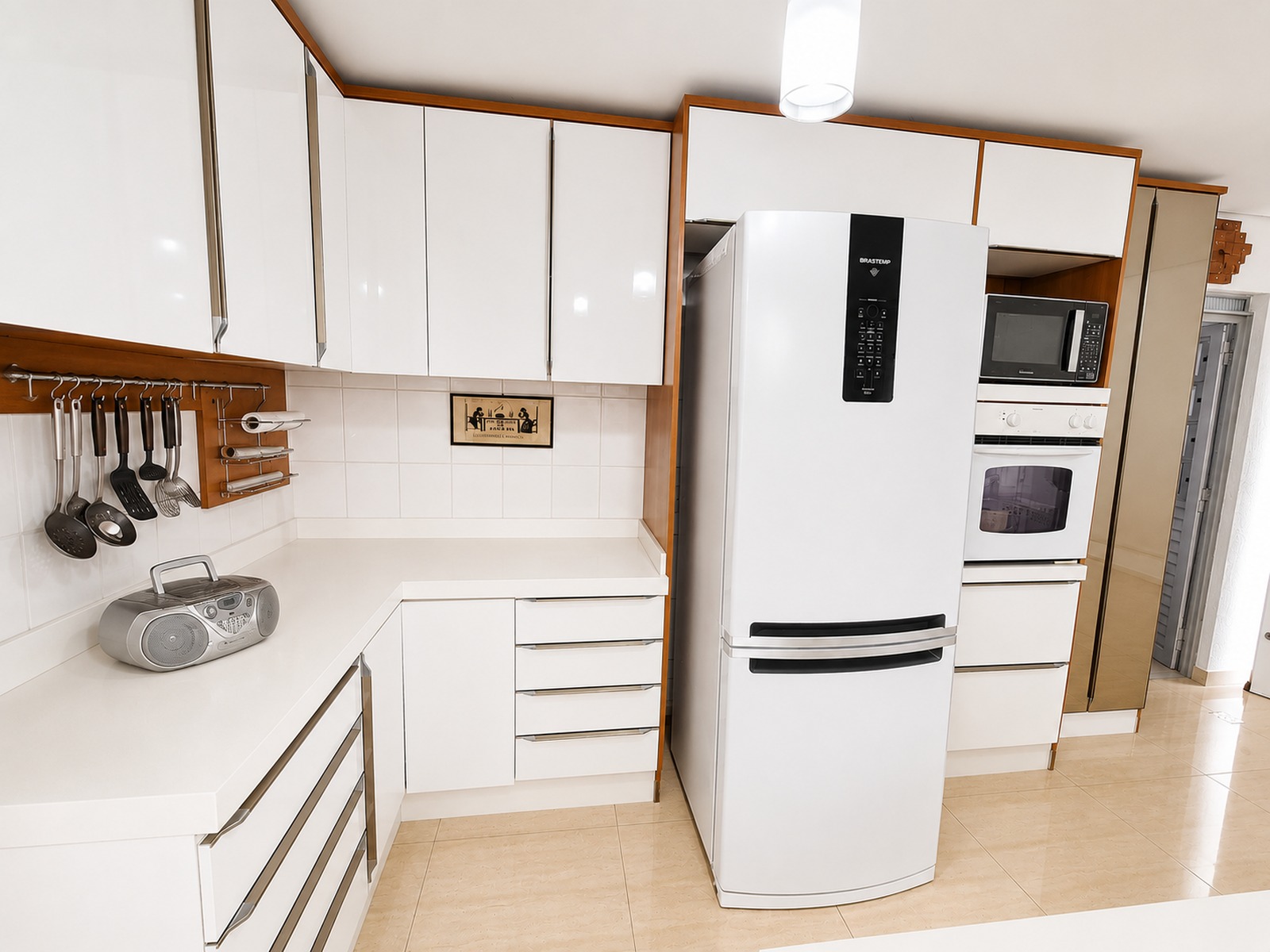 Cozinha planejada em tons claros, com armários sob medida, piso em porcelanato e forro de gesso rebaixado.