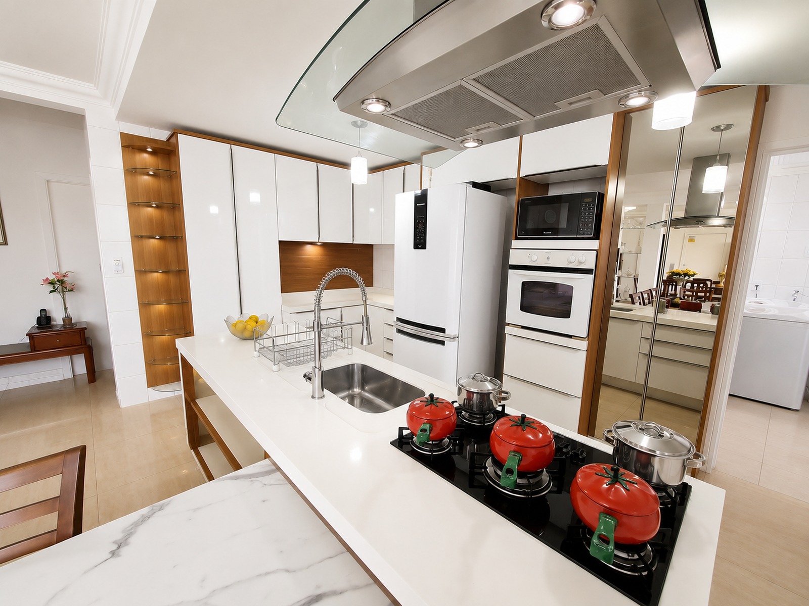 Cozinha ampla e totalmente planejada, com ilha central, cooktop, coifa e marcenaria sob medida em casa alto padrão em Florianópolis.