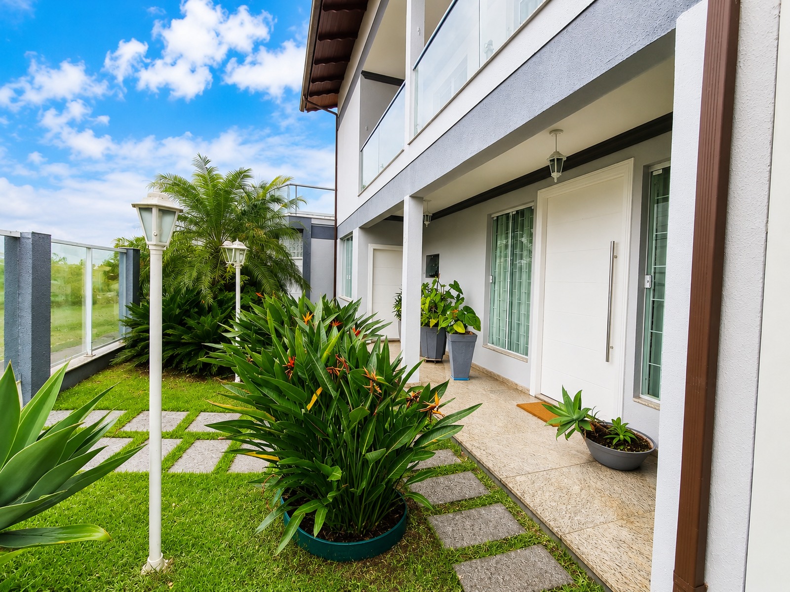 Entrada principal de casa com jardim paisagístico, acesso em pedras e fachada contemporânea em Florianópolis.