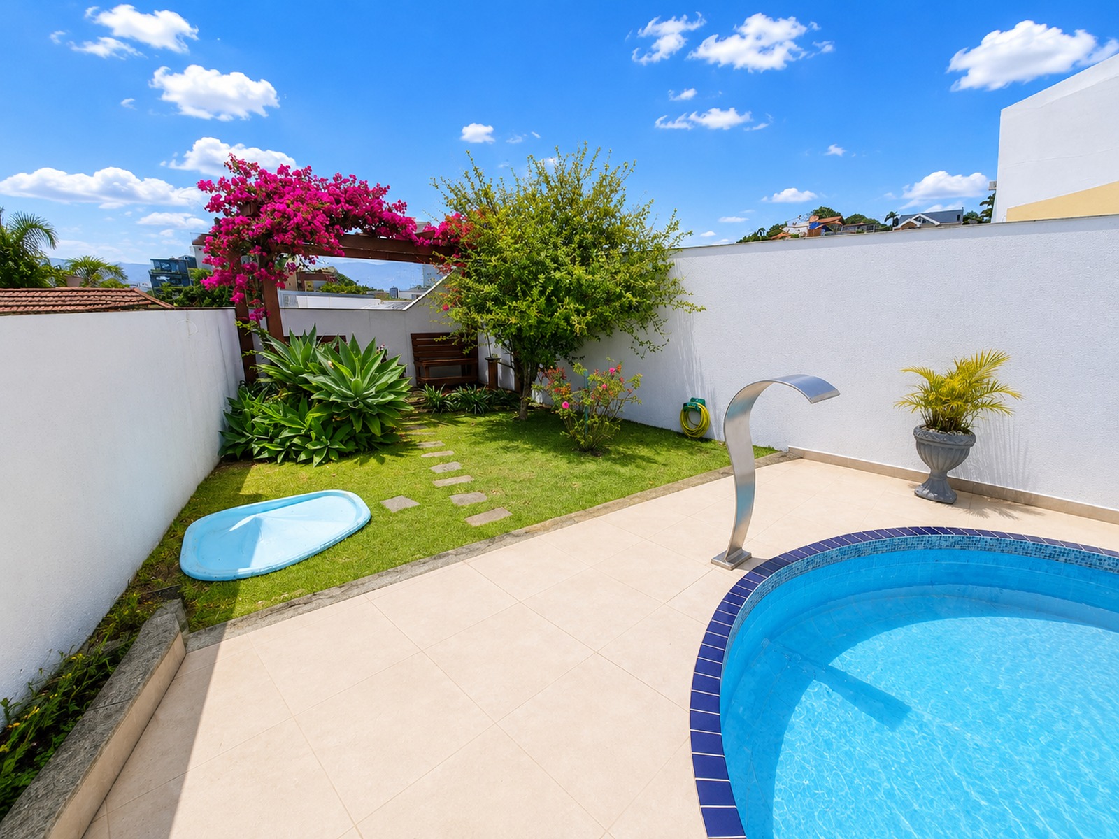 Área de lazer externa com piscina, jardim paisagístico e cascata, proporcionando privacidade e contato com a área verde.